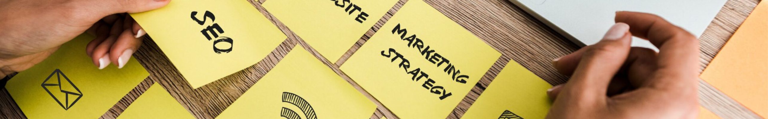 cropped view of woman touching sticky note with seo lettering near laptop on desk
